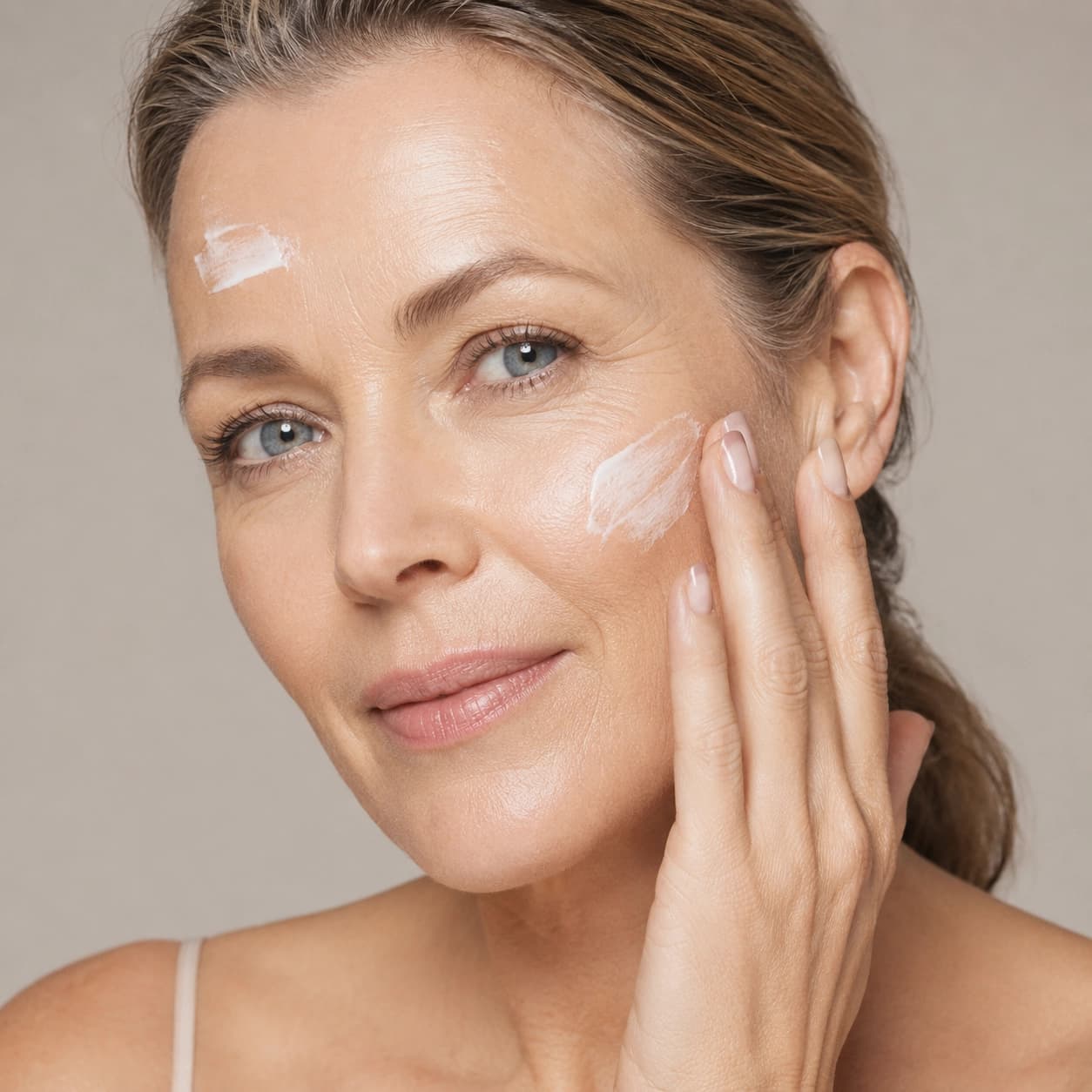 A woman in her forties applying cream to her cheek